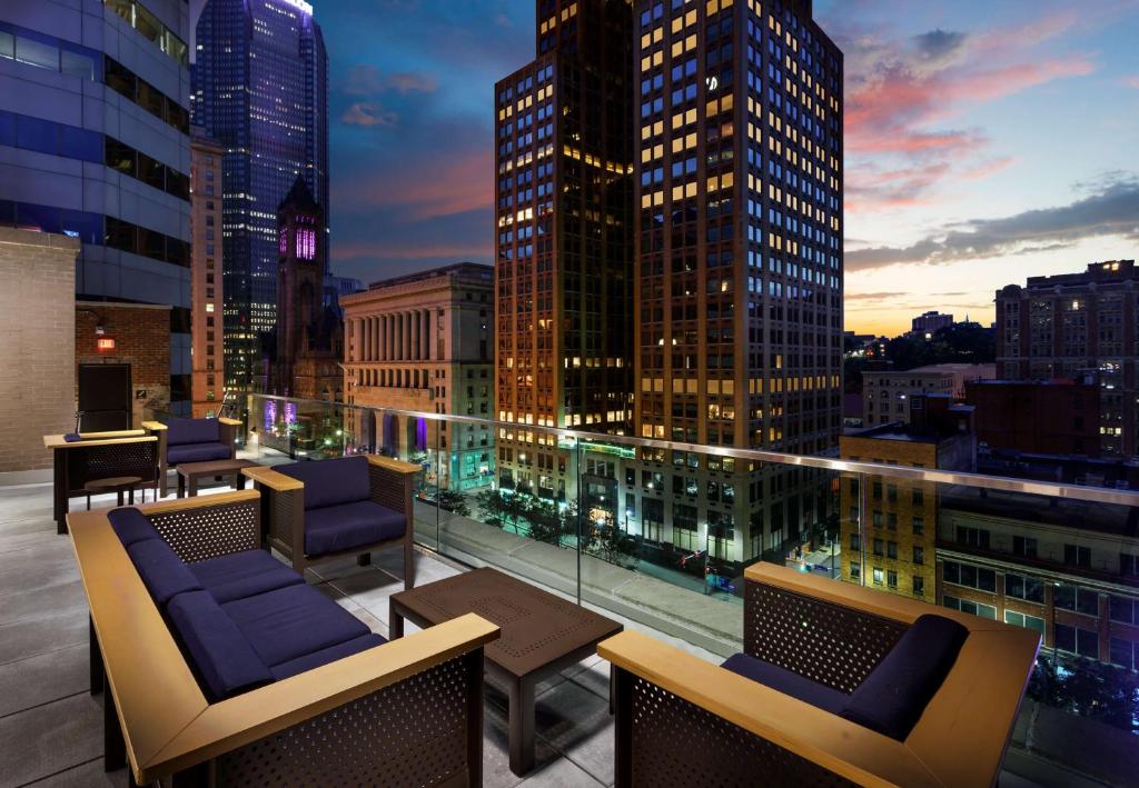 a rooftop patio with chairs and tables on a building at Joinery Hotel Pittsburgh, Curio Collection by Hilton in Pittsburgh