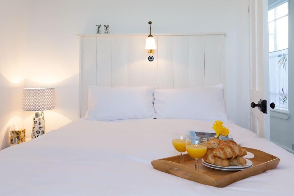 una bandeja de pan y dos vasos de zumo de naranja en una cama en Janies Cottage~ Mousehole~Eclectic Interiors & Vintage Charm en Mousehole
