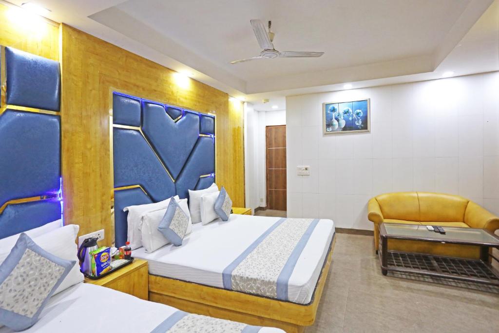 a hotel room with two beds and a chair at Hotel Preet Palace -5 Mints Walk From Nizamuddin Railway Station in New Delhi