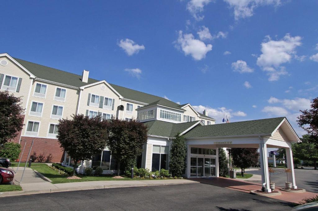 a large white building with a car parked in front of it at Hilton Garden Inn Westbury in Westbury