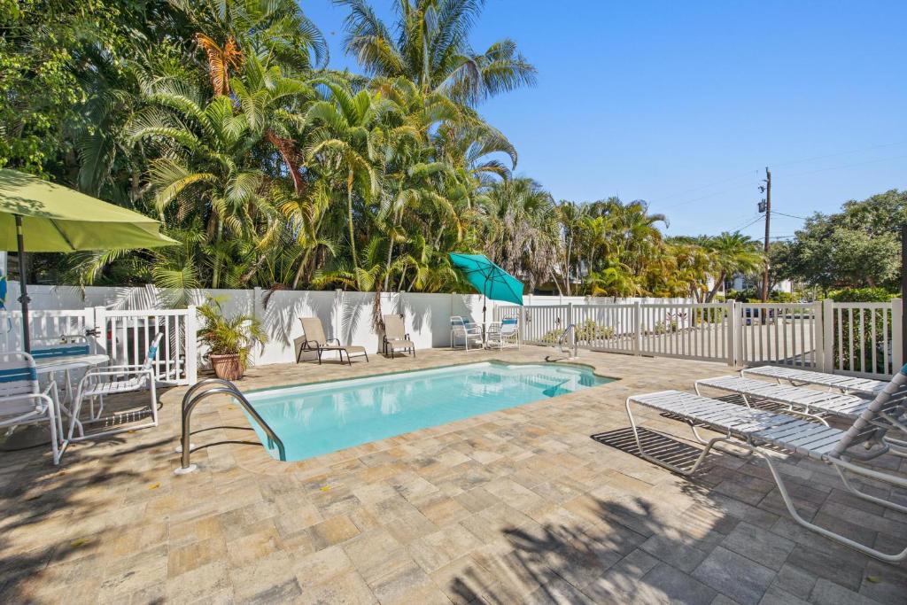 a pool with chairs and umbrellas next to a fence at Sandy Seahorse Cottage in Siesta Key