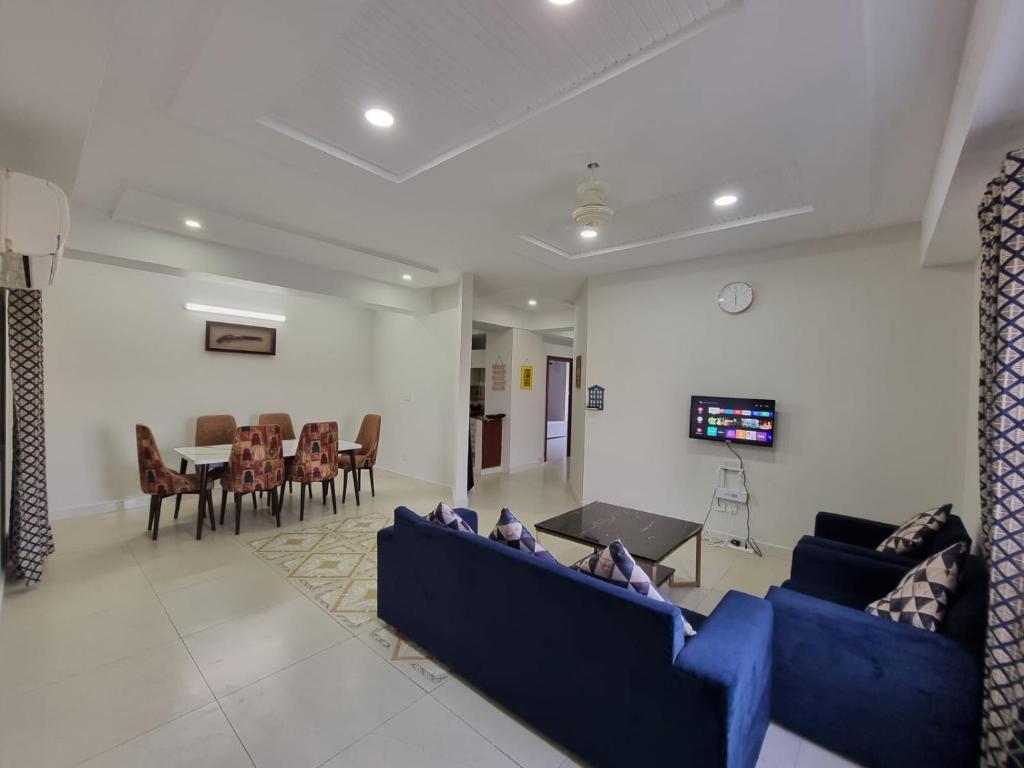 una sala de estar con 2 sofás azules y una mesa. en Three Bed Attached Bath Netflix Wifi Smart TV Parking WFH Desk, en Islamabad