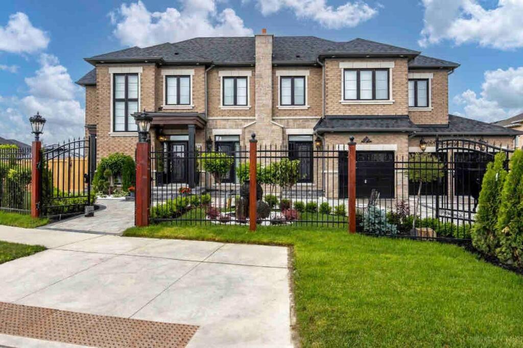 a brick house with a black wrought iron fence at Newly build Estate home 40min from Airport in Stouffville
