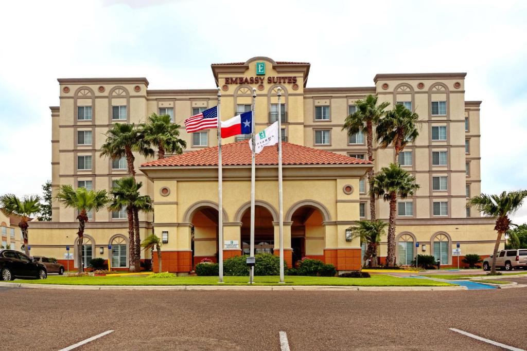hotel z dwoma flagami przed nim w obiekcie Embassy Suites by Hilton Laredo w mieście Laredo