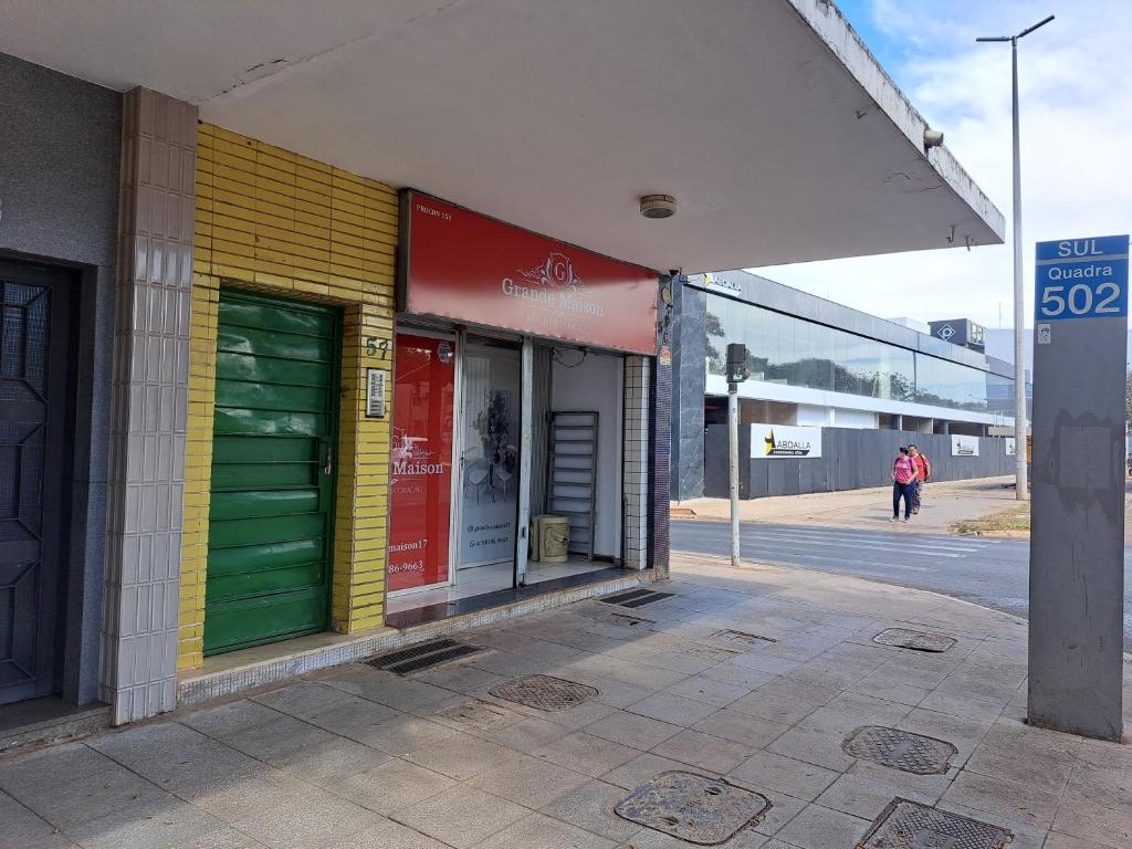 un bâtiment avec des portes vertes et jaunes dans une rue dans l'établissement Pousada do Luquinhas, à Brasilia