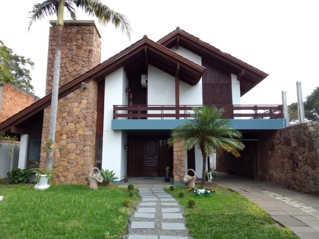 a house with a balcony and a palm tree at Pousada A Cabana in Uruguaiana
