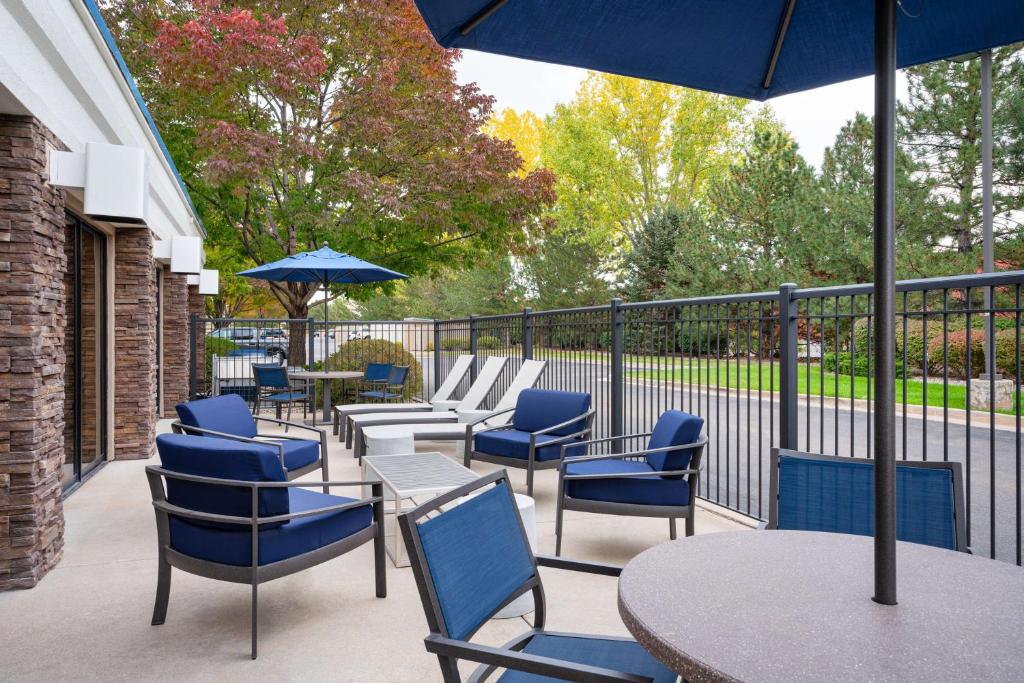 un patio con sillas, mesas y una sombrilla en Hampton Inn Loveland, en Loveland
