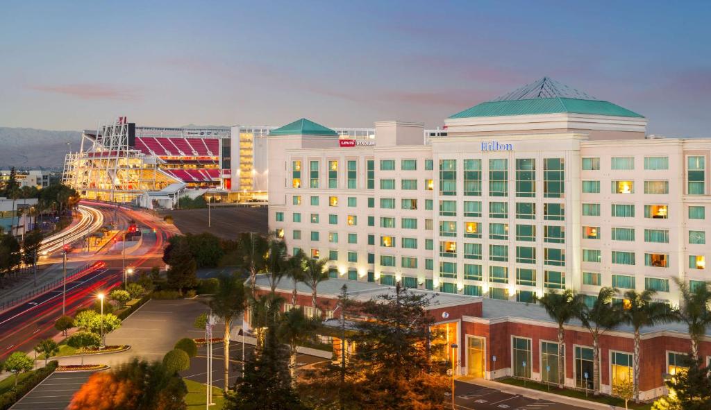 a large white building with a green roof on a city street at Hilton Santa Clara in Santa Clara