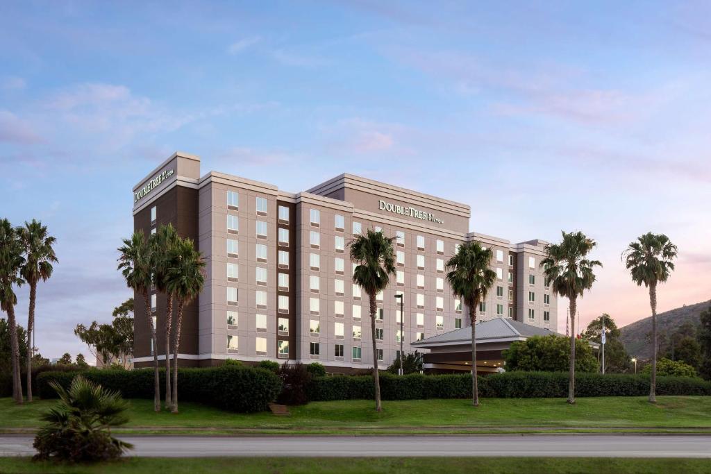 a hotel with palm trees in front of a road at DoubleTree by Hilton San Francisco Airport North Bayfront in Brisbane