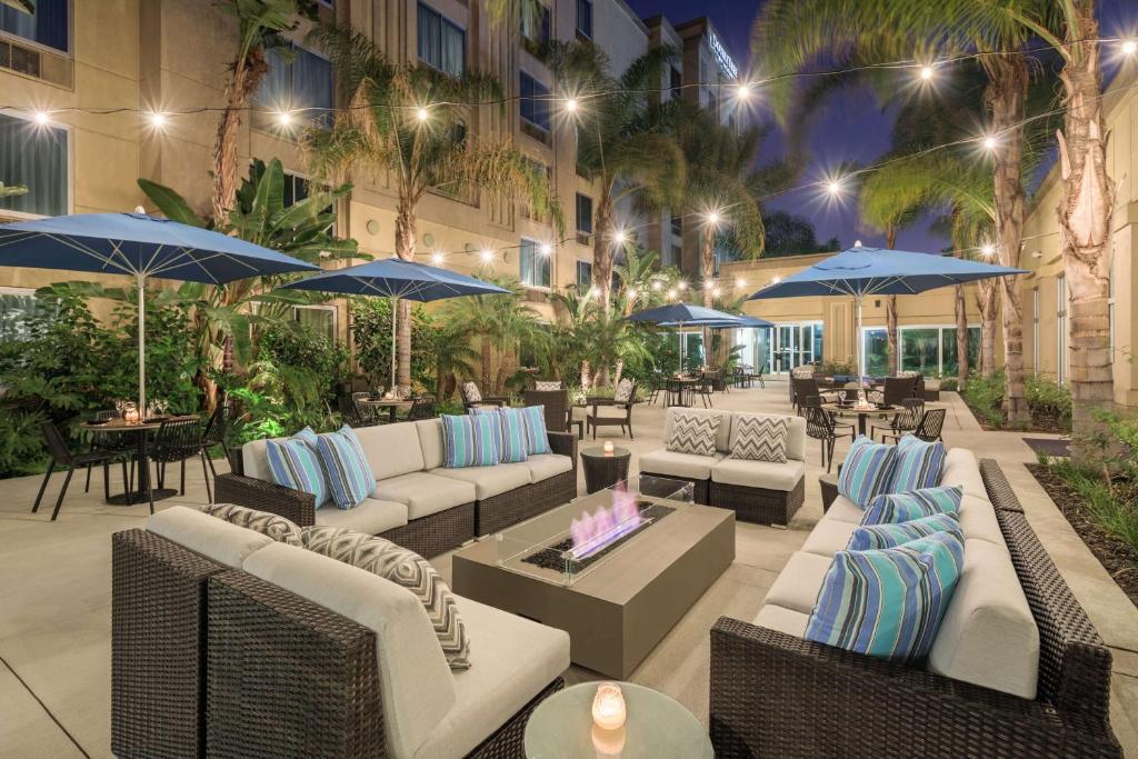 an outdoor patio with couches and umbrellas at night at DoubleTree by Hilton Los Angeles/Commerce in Commerce