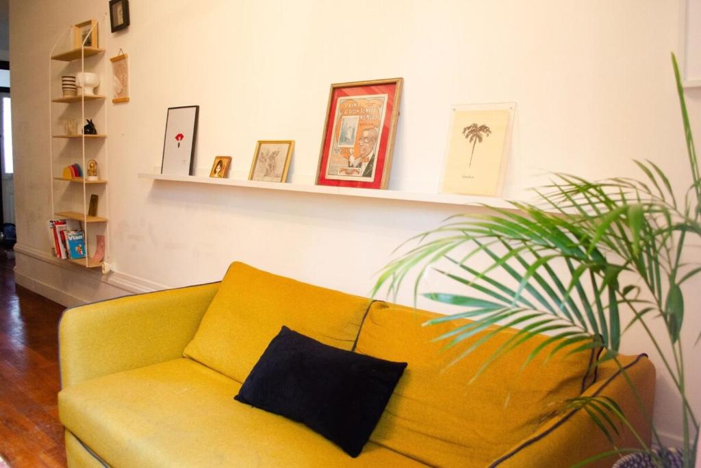 a yellow couch in a living room with a plant at Chez Julie -métro Garibaldi- Université in Lyon