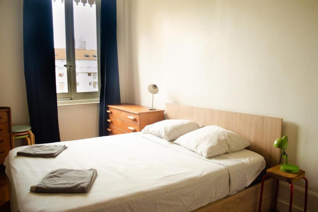 a bedroom with a bed with white sheets and a window at Chez Julie -métro Garibaldi- Université in Lyon