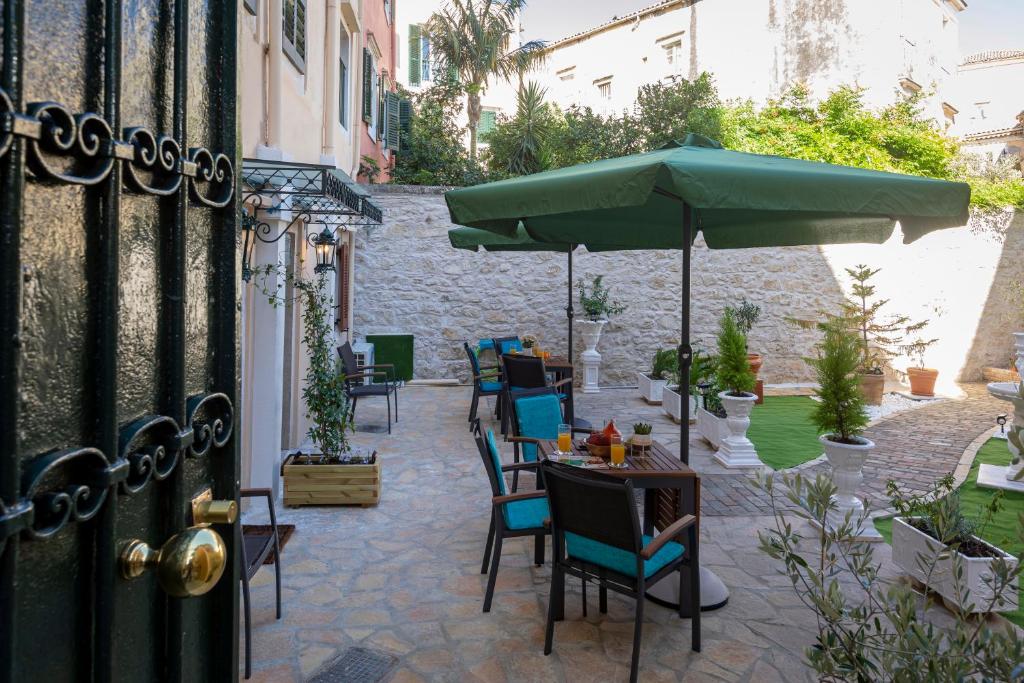 a patio with a table with an umbrella and chairs at Volto Suites in Corfu Town