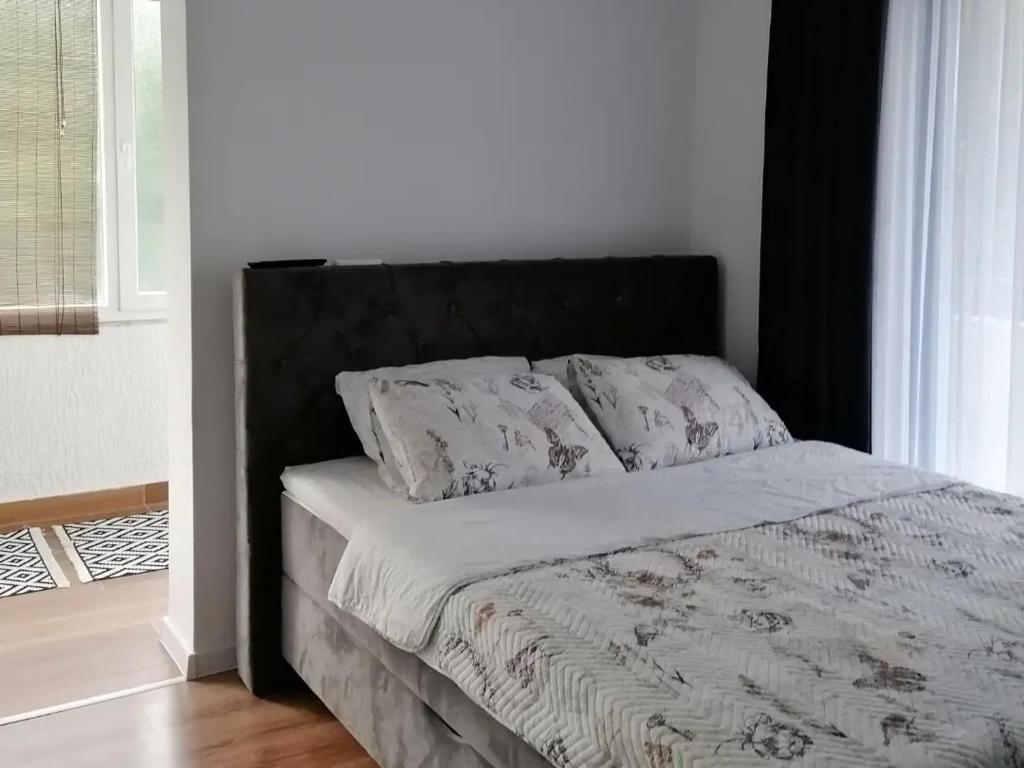 uma cama com uma cabeceira preta e duas almofadas em Apartmani Pasara em Baošići