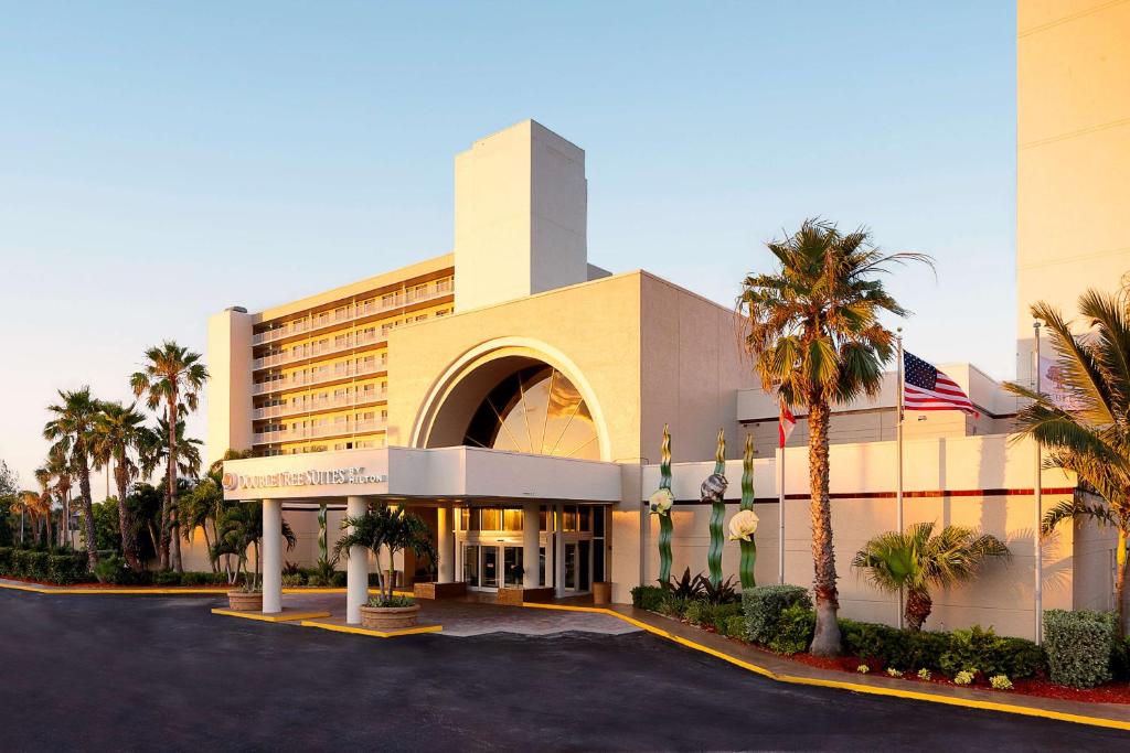 a hotel with palm trees in front of it at DoubleTree Suites by Hilton Melbourne Beach Oceanfront in Melbourne