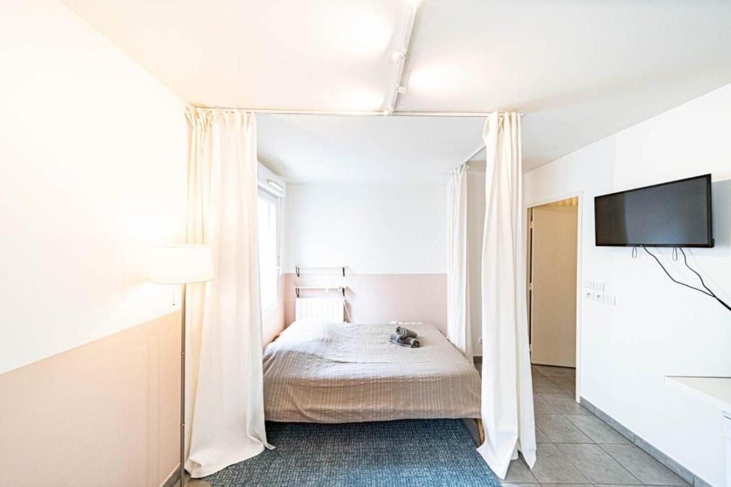 a bedroom with a bed and a flat screen tv at Le petit Montel- studio avec garage-métro Valmy in Lyon