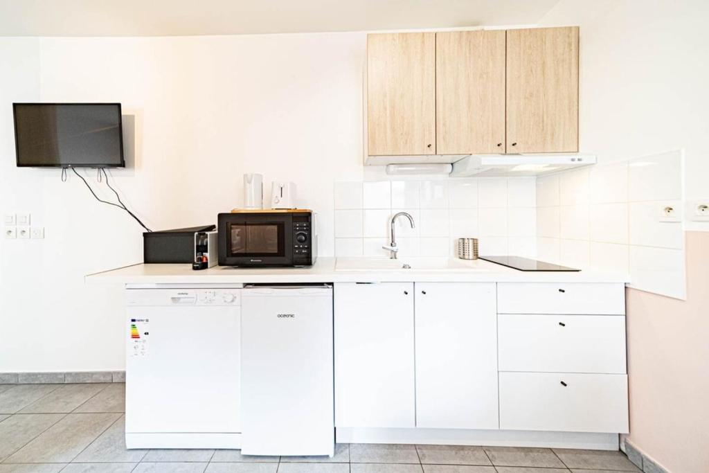a kitchen with white cabinets and a microwave at Le petit Montel- studio avec garage-métro Valmy in Lyon