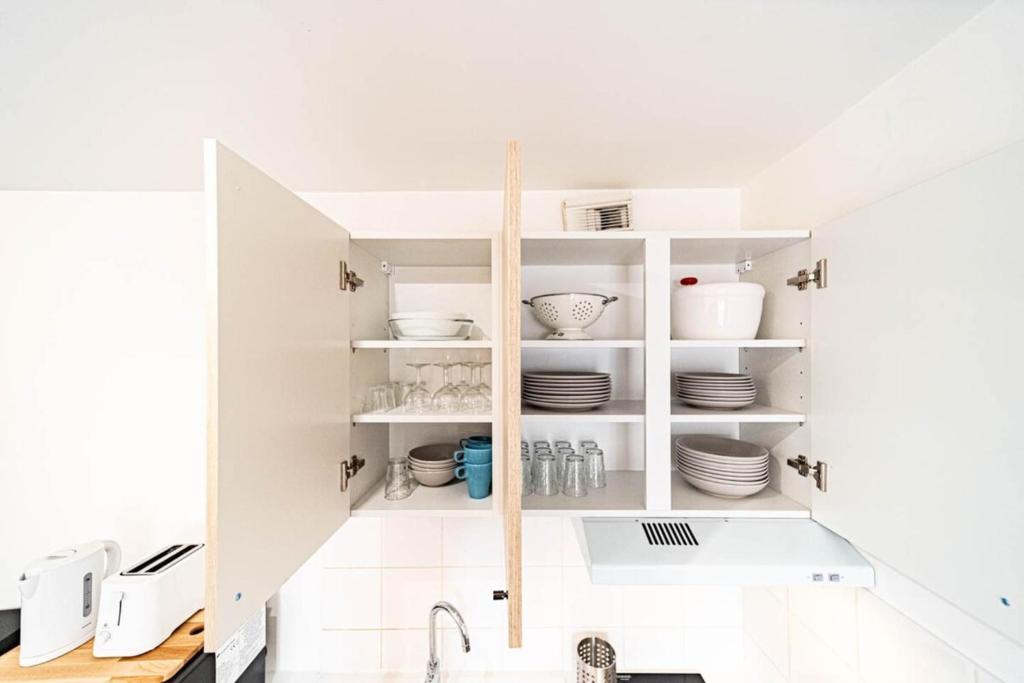 a kitchen with white cabinets and a sink at Le petit Montel- studio avec garage-métro Valmy in Lyon