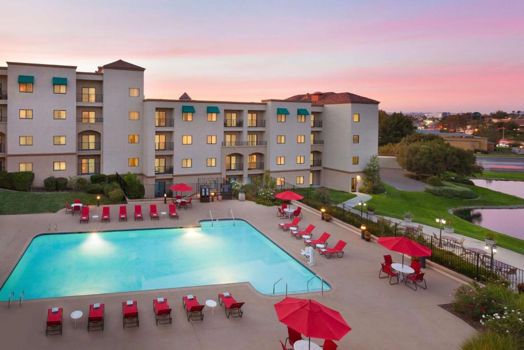 een luchtzicht op een hotel met een zwembad en rode parasols bij Embassy Suites by Hilton Temecula Valley Wine Country in Temecula