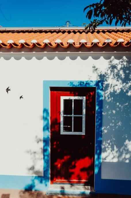 a red door on the side of a building at Casa Margarida in Albernoa