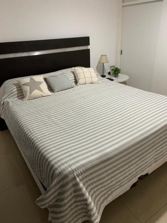a large bed with a black and white striped comforter at Departamento Centro in Santiago del Estero