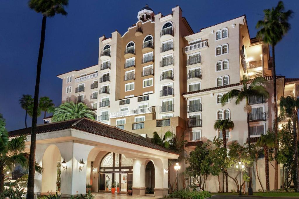 a large white building with palm trees in front of it at Embassy Suites by Hilton Santa Ana Orange County Airport in Santa Ana