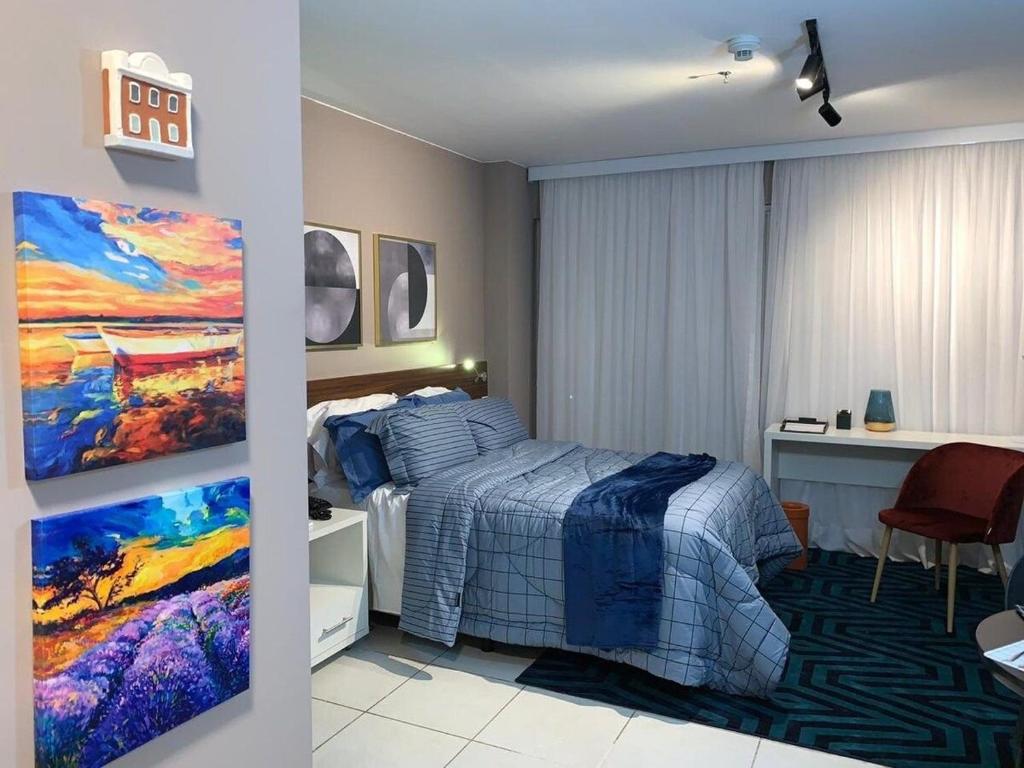 a bedroom with a bed and a desk and a painting at Flat Luxo Fusion SHN - Melhor Localização de BSB in Brasília