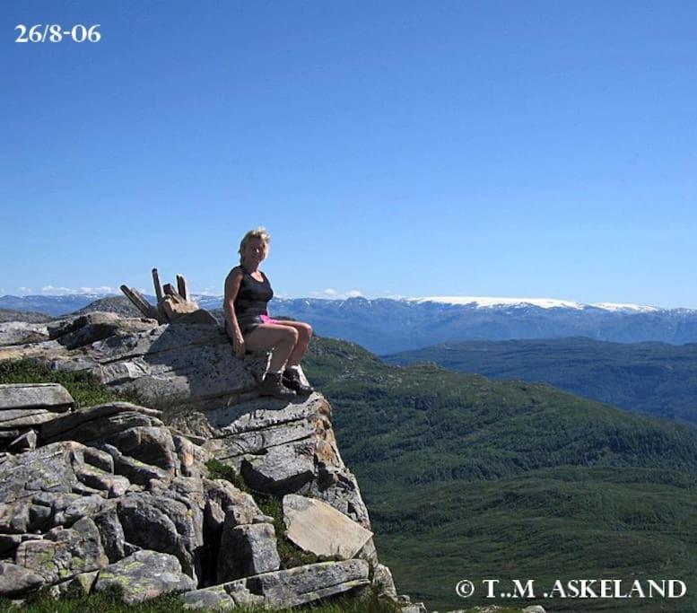 Una donna seduta sulla cima di una montagna rocciosa di Panoramahytte a Norheimsund