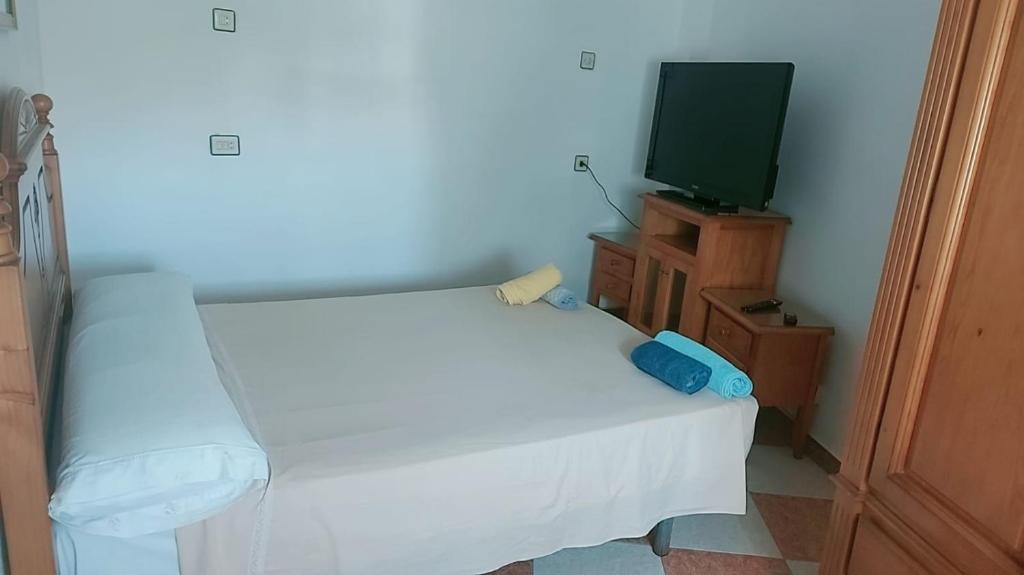 a small bedroom with a white bed and a tv at Hostal Alboran in Motril