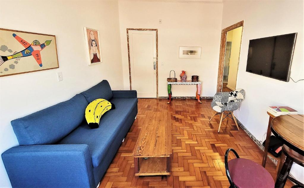 uma sala de estar com um sofá azul com uma banana em Apartamento 1 quadra da praia no Rio de Janeiro