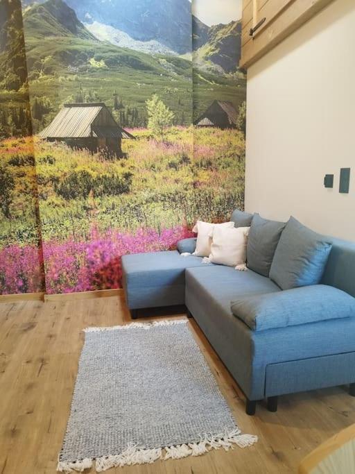 un sofá azul en una sala de estar con una pintura en Apartament u Bobaków 2 en Bańska Niżna