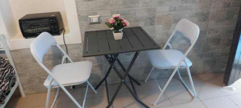 a table with three chairs and a table with flowers on it at Casa Lucia Ortigia in Siracusa