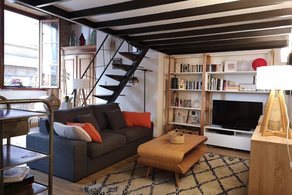 un salon avec un canapé et une télévision dans l'établissement Authentic Loft with Mezzanine & Exposed Stones Heart of Lyon, à Lyon