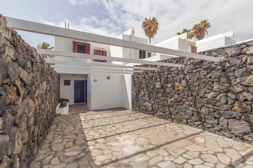 une maison blanche avec un mur en pierre dans l'établissement Adosado Maday Azul, Los Cancajos, à Breña Baja