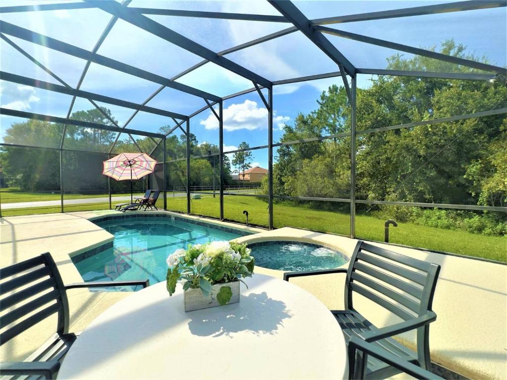a swimming pool with a table and two chairs and a glass roof at Restful Single Home with BBQ Heated Pool and SPA in Kissimmee