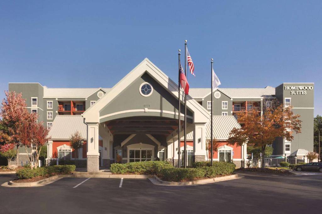 a hotel building with two flags in a parking lot at Homewood Suites by Hilton Atlanta-Alpharetta in Alpharetta