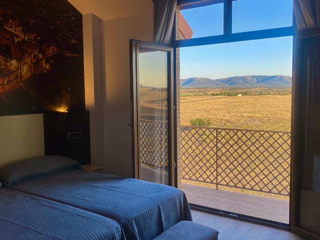 a bedroom with a bed and a window with a view at Hotel-Asador Montes Oretanos in Pulgar