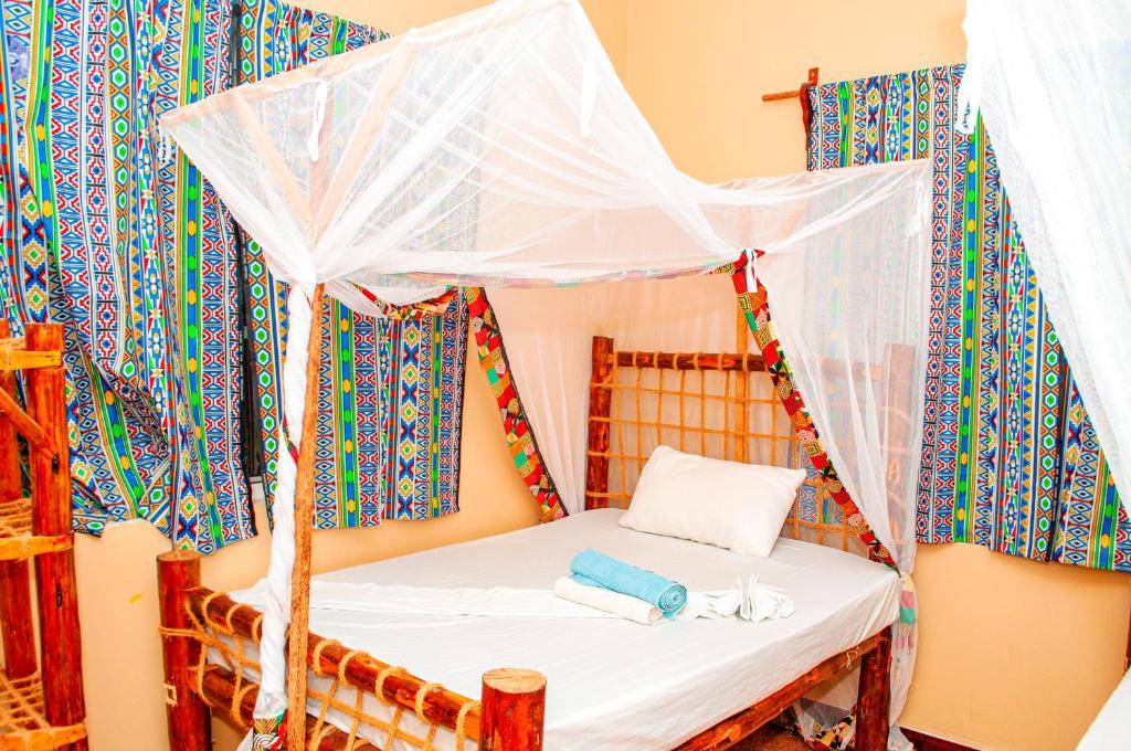 a bed in a room with a mosquito net at PALM - 2minutes walk to the beach in Nungwi