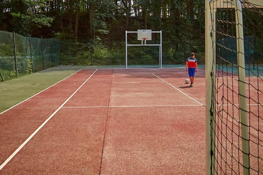 une personne debout sur un court de tennis avec un ballon de football dans l'établissement Ghislain et Pat, à Saint-Chéron