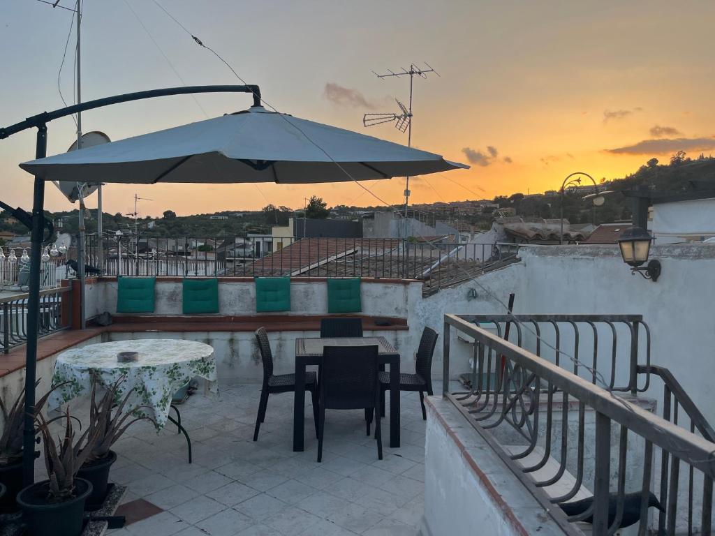 eine Terrasse mit einem Sonnenschirm, einem Tisch und Stühlen in der Unterkunft Vista da Re in Aci Castello