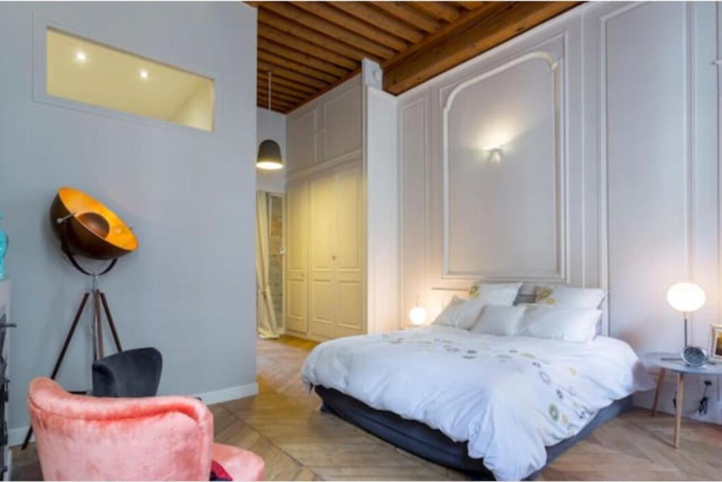 a bedroom with a white bed and a pink chair at L'escale romantique -Métro Hôtel de Ville in Lyon