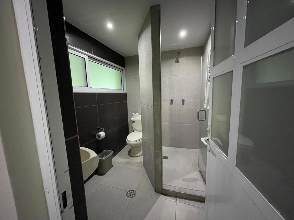 a bathroom with a toilet and a glass door at Hotel Latino in Sahuayo de José María Morelos