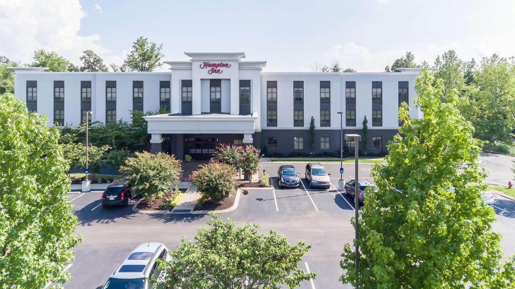 ein großes weißes Gebäude mit Autos auf einem Parkplatz in der Unterkunft Hampton Inn White House in White House