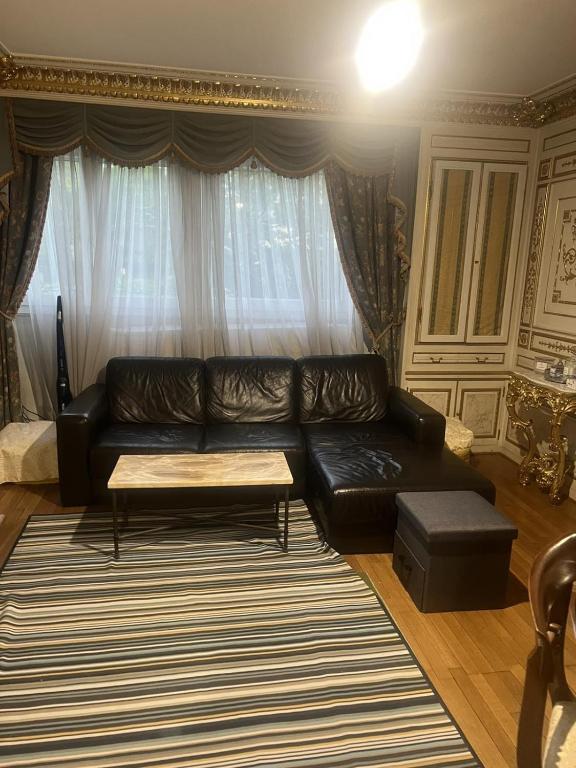 a living room with a black leather couch and a table at Cozy Nice Apartment Room Free Wi-Fi an parking in Asnières-sur-Seine