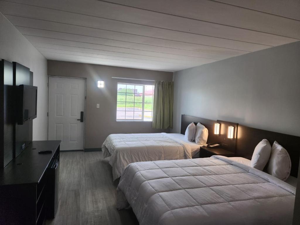 Habitación de hotel con 2 camas y TV de pantalla plana. en Royal Inn Hotel en Indianápolis