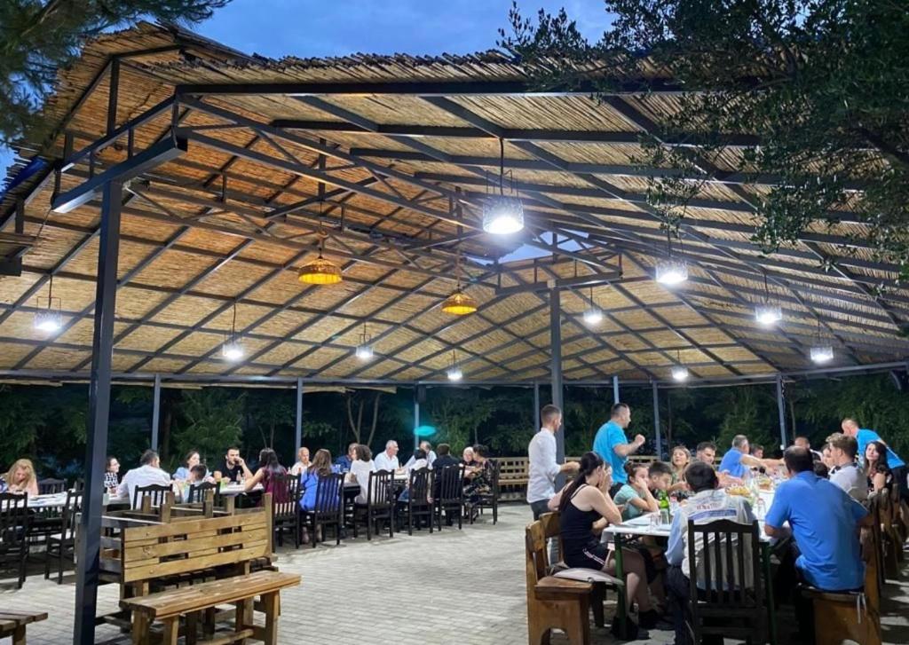 a group of people sitting at tables under a pergola at Lundra in Gramsh