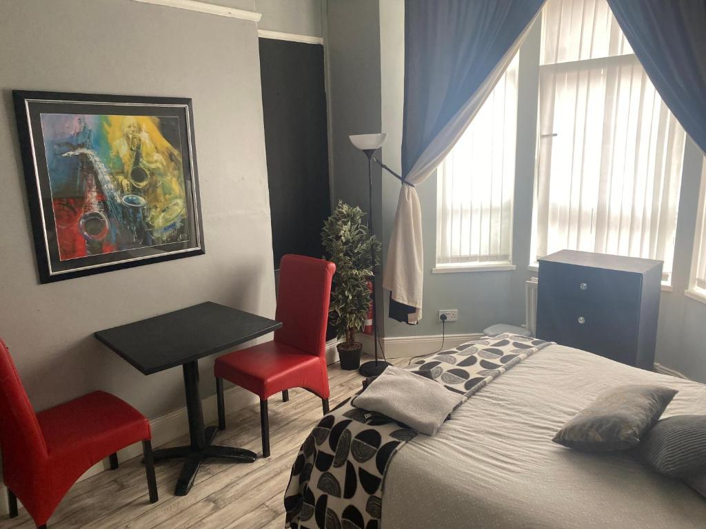 ベルファストにあるbnbのベッドルーム1室(ベッド1台、テーブル、赤い椅子2脚付)