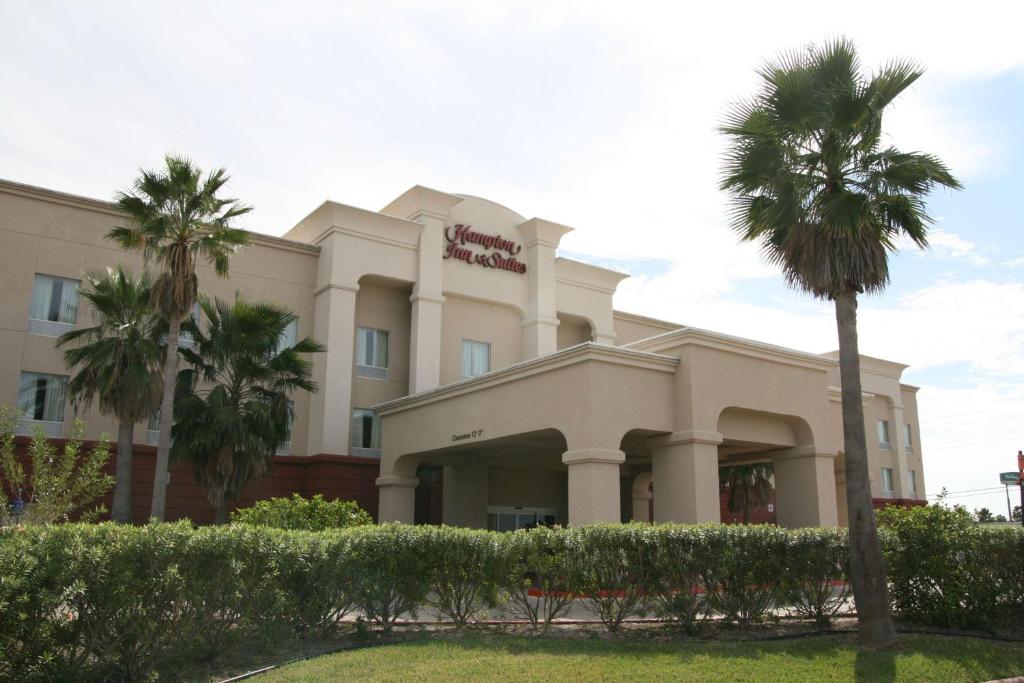 a hotel with palm trees in front of it at Hampton Inn and Suites-Brownsville in Brownsville