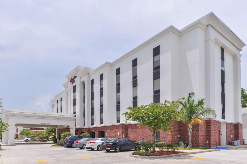 a large white building with cars parked in a parking lot at Hampton Inn Gonzales in Gonzales