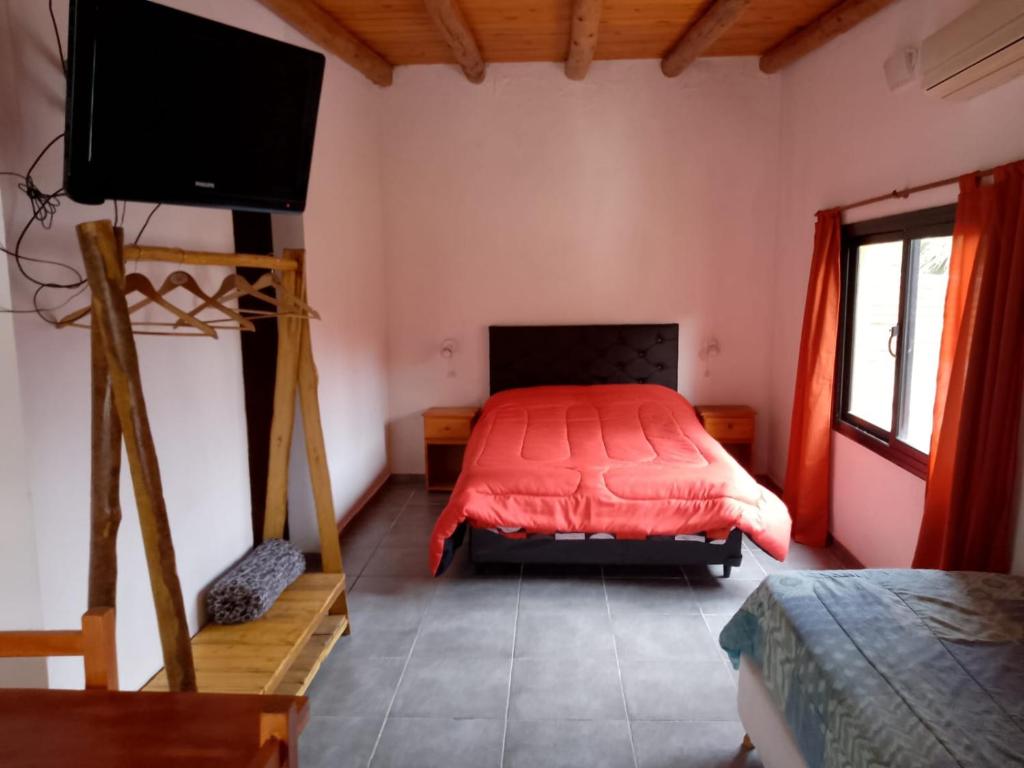 1 dormitorio con 1 cama y TV de pantalla plana en Diversidad serrana en Huerta Grande
